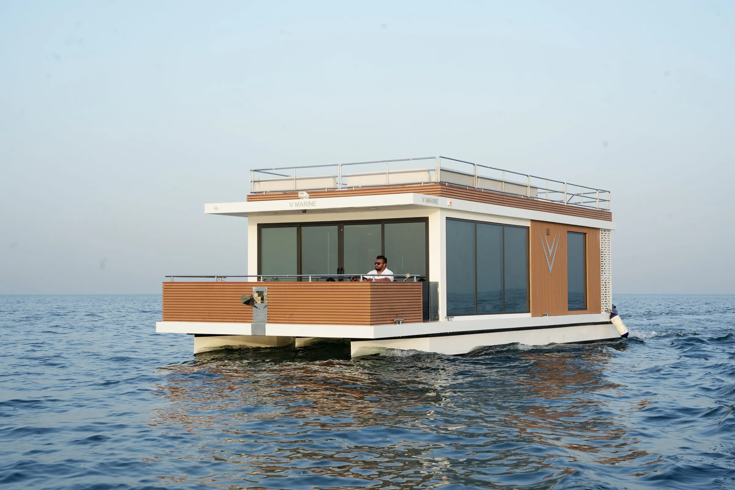 Aquator HotelYacht on calm water, its timber-clad cabin framed by glass
